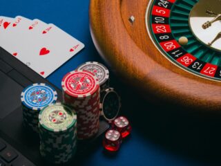 Close-up of playing cards and a computer on a brown wooden table.