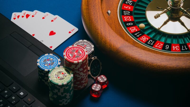 Close-up of playing cards and a computer on a brown wooden table.